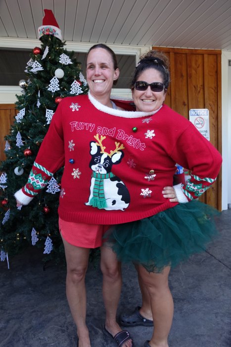 adults in front of christmas tree in ugly sweater